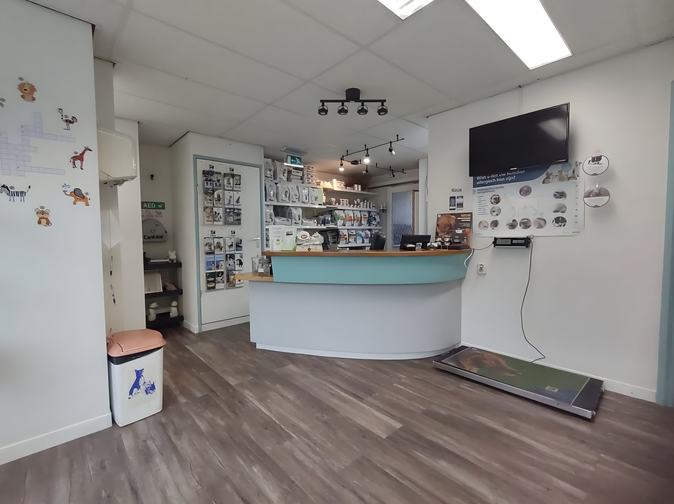 De balie van Dierenkliniek Hoograven met een turquoise toonbank, een houten bovenrand en schappen met dierenartikelen erachter.